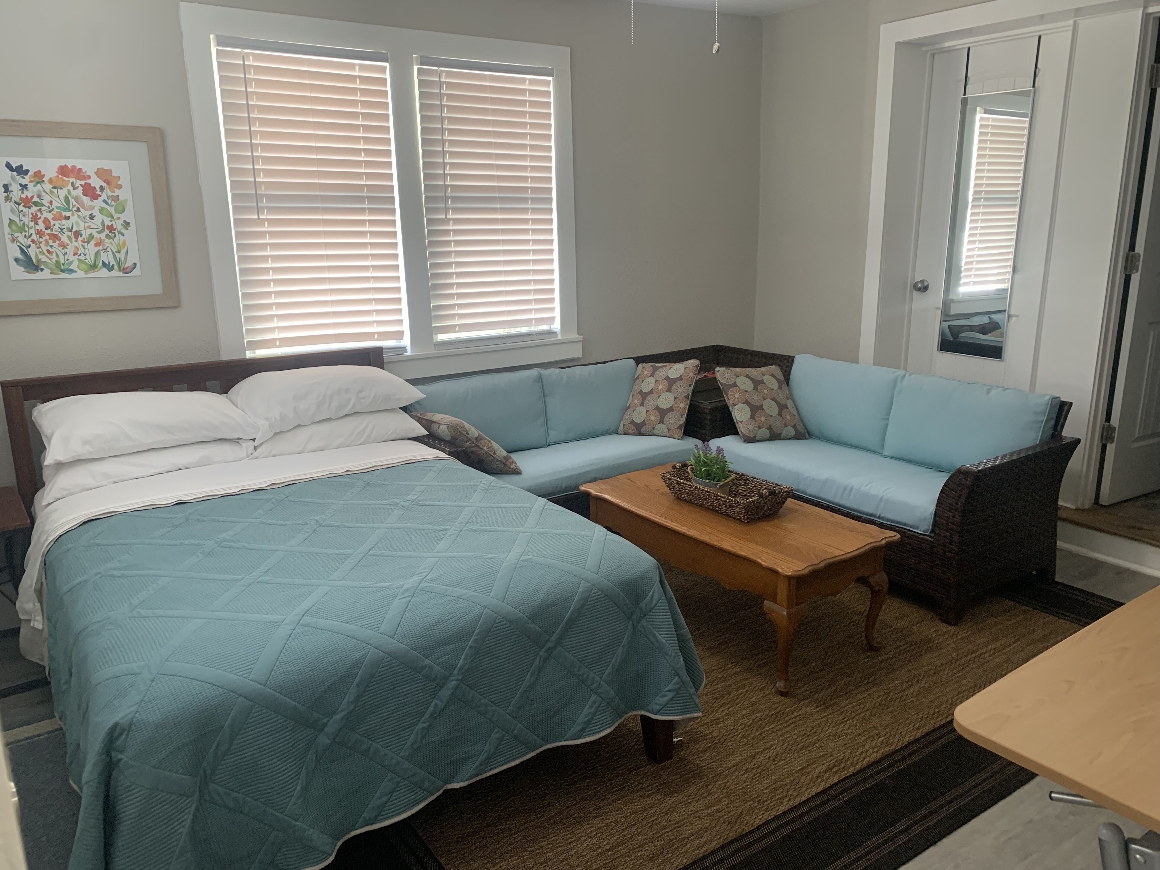 A bedroom with a bed, a sofa, a coffee table, and a door.