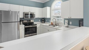 A modern kitchen with white cabinets, stainless steel appliances, and a large window providing natural light. - 3br/2ba condo in Barefoot Resort & Golf (North Myrtle Beach, SC)  (North Myrtle Beach)