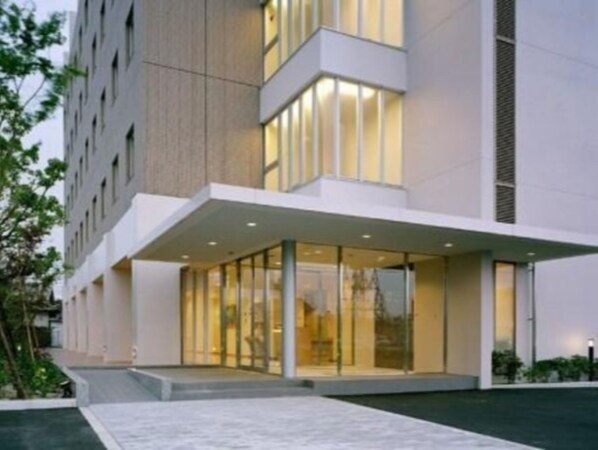 Contemporary building with a flat roof and large glass windows, featuring a prominent entrance with a covered walkway.