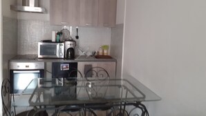 Una cocina moderna con una mesa de comedor de vidrio, electrodomésticos de acero inoxidable y un salpicadero de azulejos.