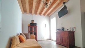 A bedroom with a bed, wooden floor, a wardrobe, a TV, and a window. - House in the woods. (Dolo)