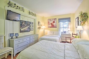 Ein Hotelzimmer mit zwei Betten, einem Fernseher, einem Klavier-Kunstwerk und einem Violinbild.