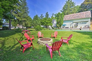 Ein Garten mit Feuerstelle, roten Adirondack-Stühlen und einem Poolbereich.