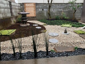 Stroll through a serene garden featuring a traditional Japanese lantern, stepping stones, and lush greenery.