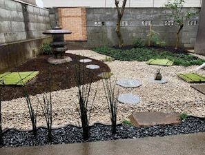 Stroll through a serene garden featuring a traditional Japanese lantern, stepping stones, and lush greenery.