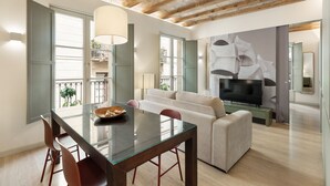 A modern living room with a glass dining table, a sofa, a TV, and a balcony with plants. - Modern and comfortable apartment in the heart of the city (Barcelona)