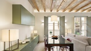 A modern living room with a glass dining table, green cabinets, and a beige sofa. - Modern and comfortable apartment in the heart of the city (Barcelona)