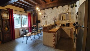 Una cocina rústica con una mesa de madera, sillas, un reloj y un refrigerador.
