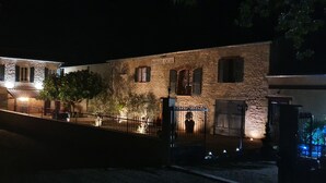 Un edificio de piedra con un cartel que dice "MAS DE DOAT" iluminado por luces exteriores, de noche.