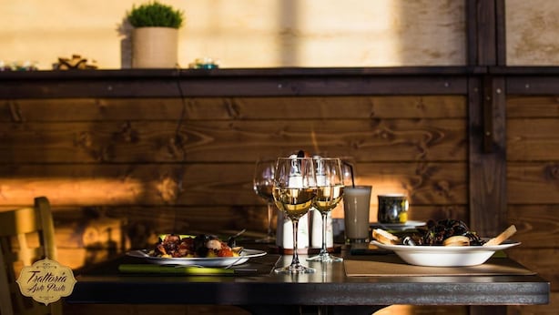 Una mesa de comedor con un plato de comida, dos copas de vino y una vela.