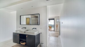 Un baño moderno con dos lavamanos, un espejo grande y un mueble oscuro.
