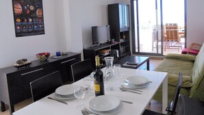 Un coin repas avec une table dressée pour deux personnes, un téléviseur et une affiche du système solaire accrochée au mur.