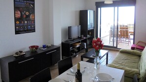 Un salon comprenant une table à manger, un téléviseur, un meuble et une affiche du système solaire.