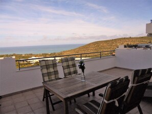 Une terrasse avec une table et des chaises, offrant une vue sur un paysage côtier.