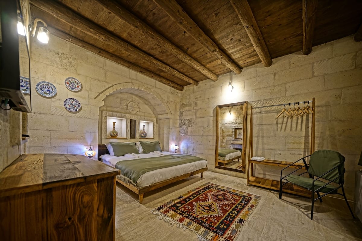 A rustic room with a wooden bed, a mirror, and a hanging chair.