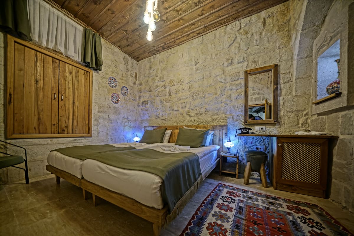A rustic bedroom with a wooden bed, a desk, and a mirror.