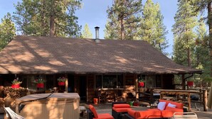 A wooden cabin with a deck, outdoor seating, and hanging flower baskets. -  Beautiful Log home outside of Sisters, OR (Sisters)
