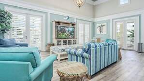 A spacious living room with a large television, comfortable seating, and a decorative ceiling light.