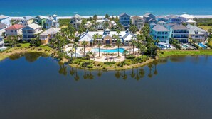 A coastal resort with multiple buildings, a central pool, and a large body of water reflecting the structures.