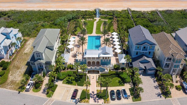 A large resort with a central pool, multiple guest houses, and a beach view.