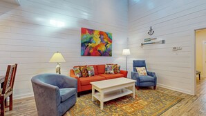 A living room with a sofa, two armchairs, a coffee table, and a colorful abstract painting on the wall. - PB302 Community Pool and Parking for 3 (Port Aransas)