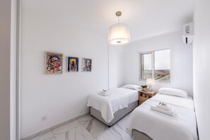 Une chambre moderne avec deux lits, une grande fenêtre et des œuvres d’art accrochées au mur.