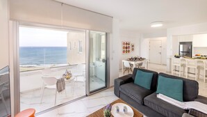 Eine moderne Wohnung mit Balkon und Meerblick, einem Essbereich und einer Küche.
