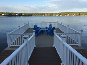 Una terraza con mesa y sillas, con vistas a un lago tranquilo y una orilla lejana.