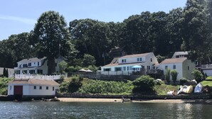 A lakeside property with multiple houses, a dock, and a stone wall. - Direct waterfront vacation rental, family friendly, pets allowed (East Lyme)