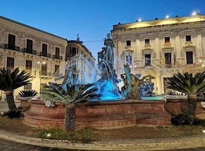 A historic building with a fountain in the center, surrounded by palm trees.