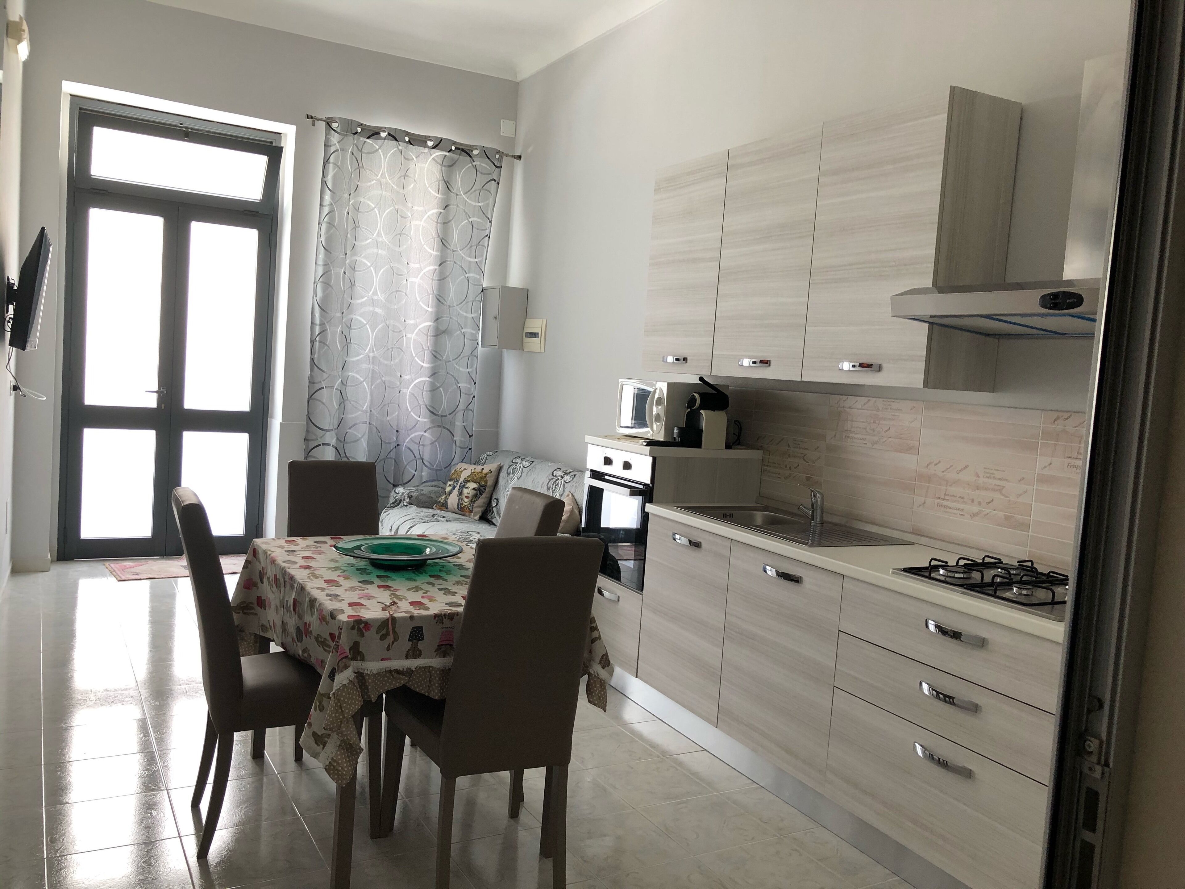 A modern kitchen with a dining area, featuring a table with chairs, a microwave, and a stove.