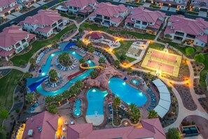 A resort with multiple swimming pools, a water slide, tennis courts, and lounge areas.