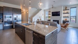 A modern kitchen with granite countertops, stainless steel appliances, and pendant lighting.