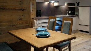 Une cuisine moderne avec des meubles en bois, une table à manger avec de l’assiette bleue et un four encastré.