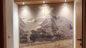 Une pièce dotée d’un plancher en bois et d’une grande porte coulissante ornée d’une fresque représentant un paysage de montagne.