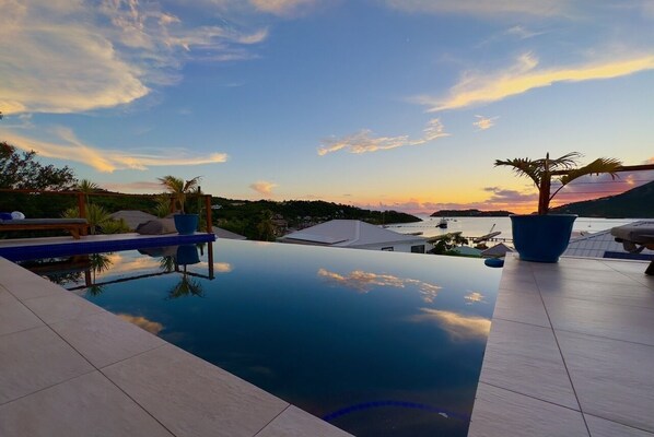 Ein Infinity-Pool mit freiem Blick auf den Sonnenuntergang und die umliegende Landschaft.
