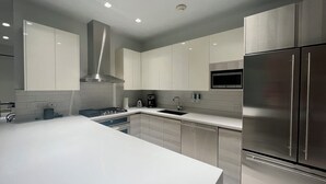 A modern kitchen with white cabinetry, stainless steel appliances, and recessed ceiling lighting. - Waykiri Unit C-08 Luxurious New Apartment, Noord (Noord)