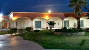 A building with a series of arched windows and a well-maintained lawn. - Hotel Jimenez Plaza (Jimenez)