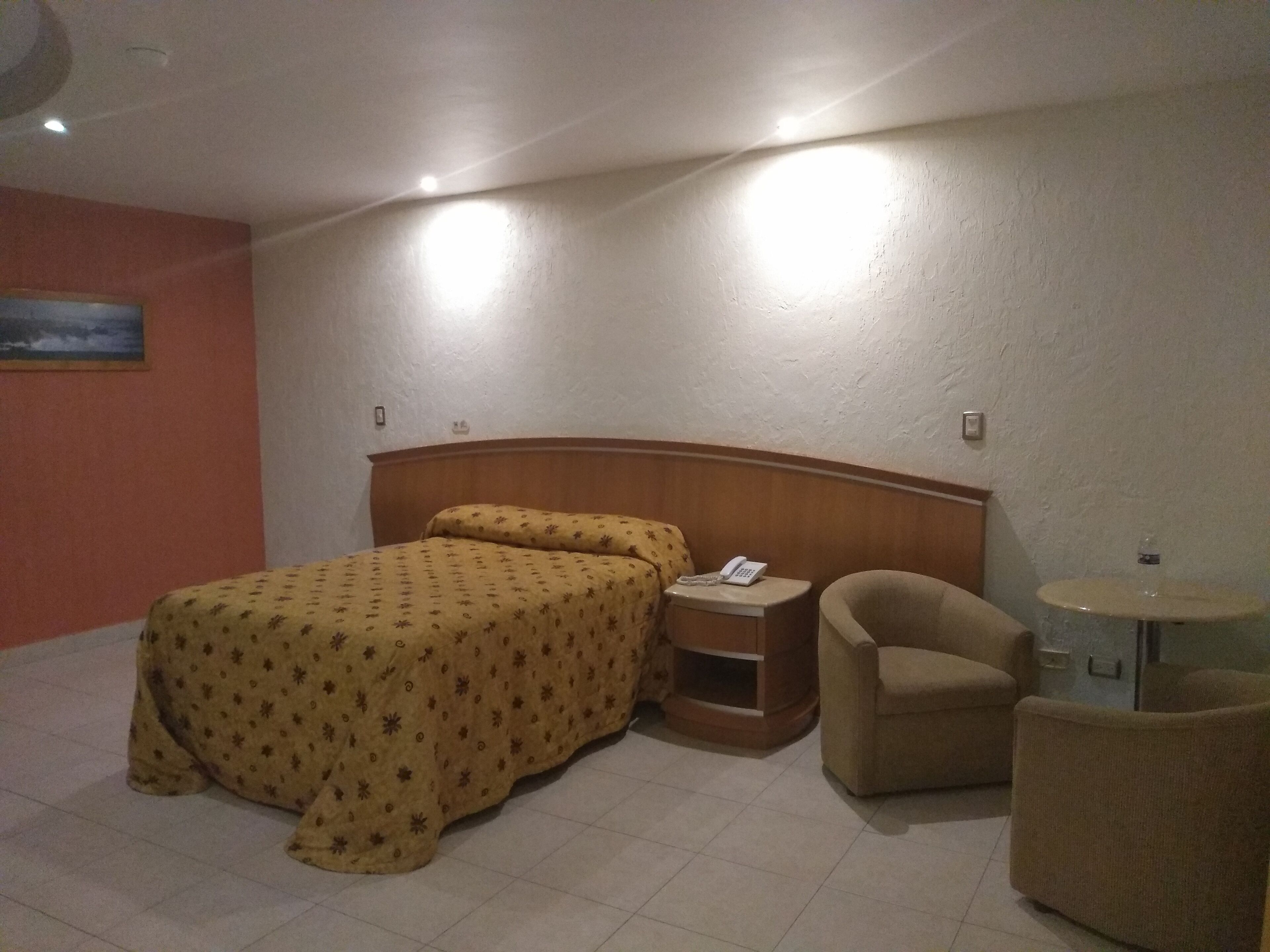 Una habitación de hotel con una cama, una mesita de noche, una silla y una pequeña mesa.