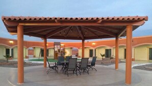 An outdoor patio with a covered dining area, surrounded by a building with multiple rooms. - Hotel Jimenez Plaza (Jimenez)