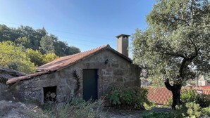Un edificio de piedra con techo de tejas, chimenea y una puerta.