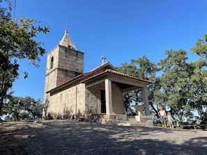 A small stone chapel with a bell tower, surrounded by trees.