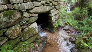 Una estructura de piedra por donde fluye un arroyo.