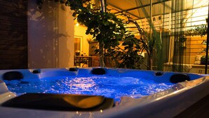 Ein Whirlpool mit blauem Licht, umgeben von Zimmerpflanzen und einer Glaseinfassung.
