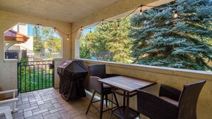Eine überdachte Terrasse mit Tisch, Stühlen, einem Grill und Blick auf einen mit Schnee bedeckten Baum.