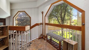 Eine Holztreppe mit weißer Geländer führt zu einem Balkon mit Blick auf Bäume.