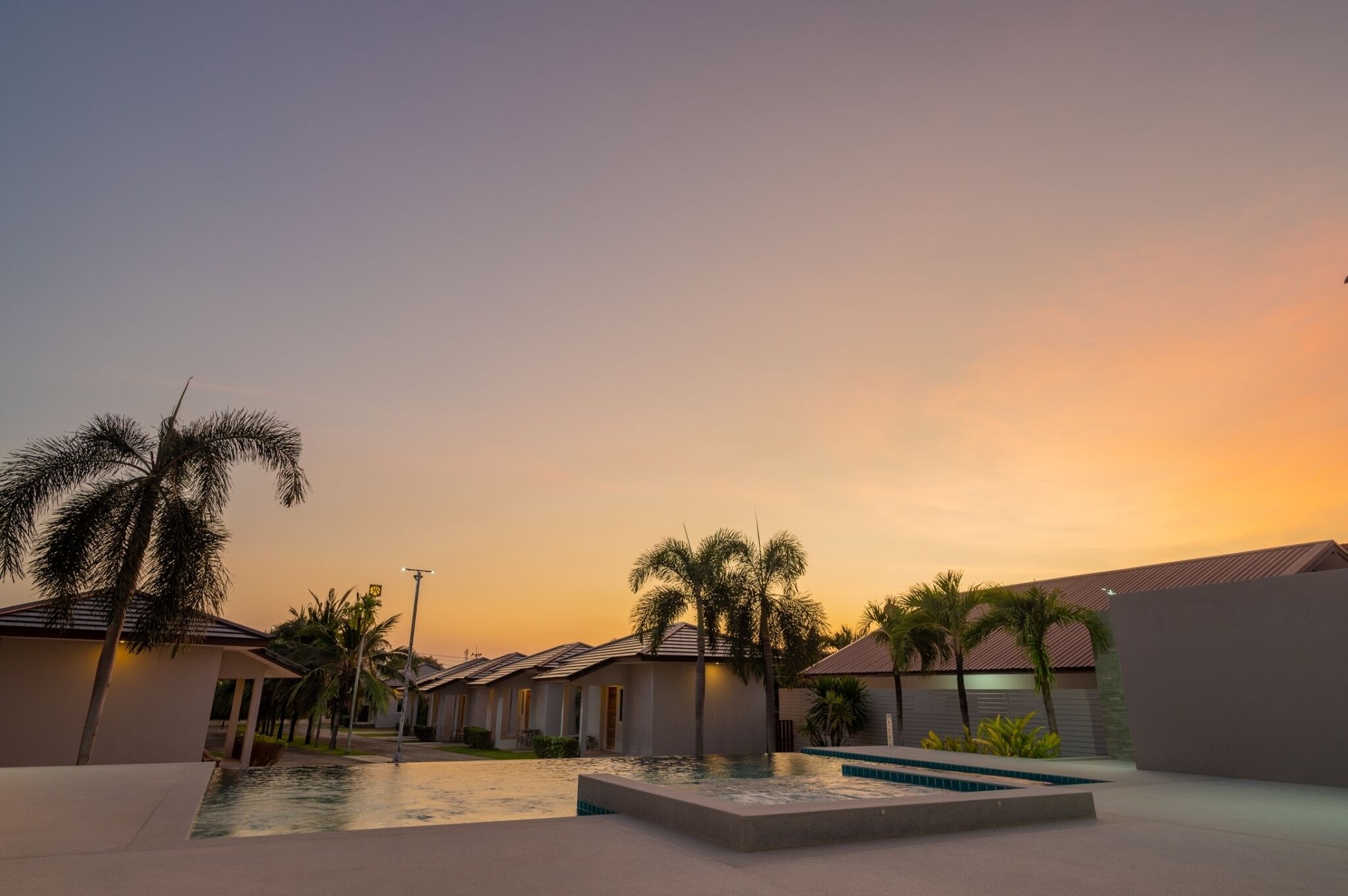 A resort with a swimming pool, palm trees, and villas.