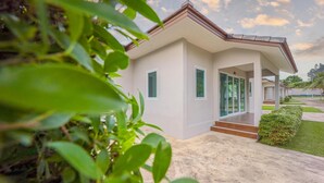 Une maison moderne dotée d’un porche abrité, de grandes fenêtres et d’une pelouse bien entretenue.
