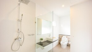 Une salle de bain moderne avec une douche à parois de verre, un lavabo avec un miroir et des toilettes.
