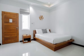 Een slaapkamer met een houten deur, een nachtkastje, een bed met witte lakens en een klok aan de muur.